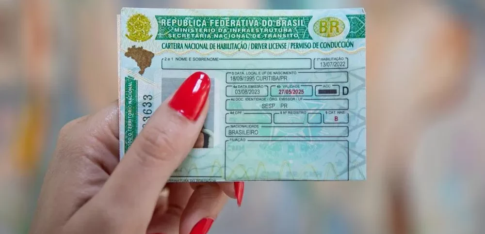 Carteira Nacional de Habilitação sendo segurada por mulher com destaque para documento oficial brasileiro