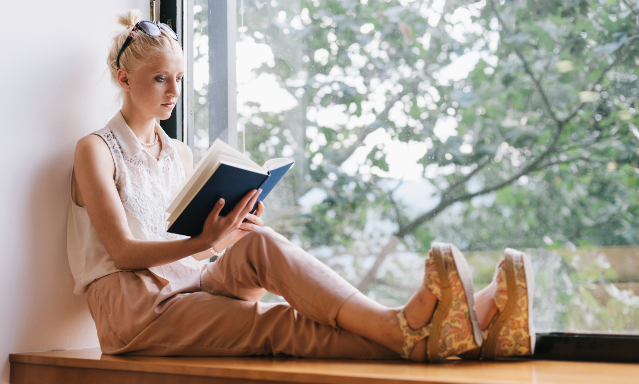 jovem lendo livro perto da janela representando crescimento da leitura no Brasil