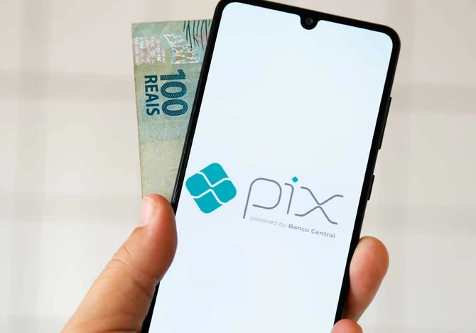 pagamento via Pix em celular com nota de real ao fundo no Brasil