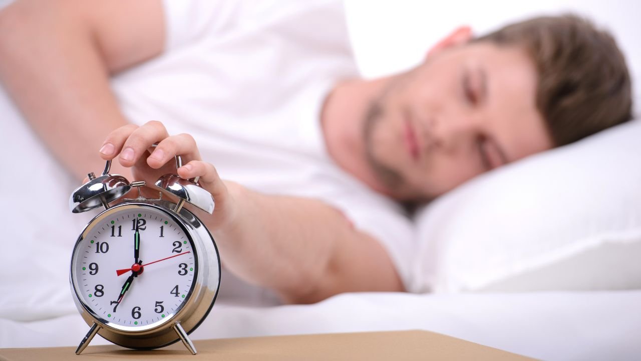 homem acordando com despertador representando o tempo ideal de sono para controlar a glicose