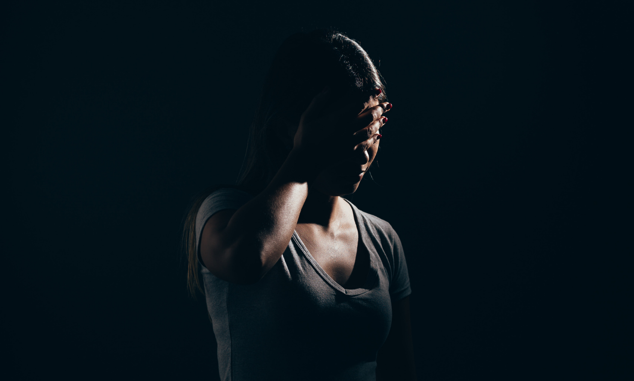 jovem cobrindo o rosto em ambiente escuro representando impacto do uso excessivo das redes sociais na saúde mental de adolescentes