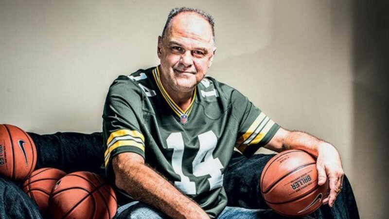 Homem com bola de basquete sorrindo.