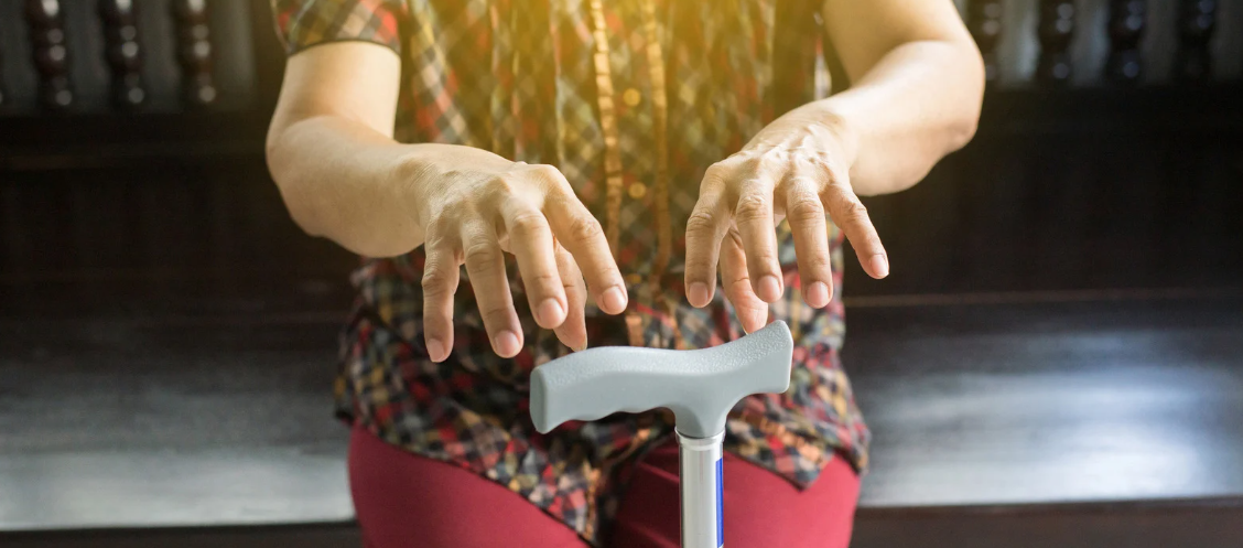mãos com tremores segurando bengala em imagem que representa sintomas do Parkinson