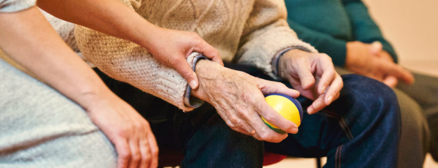 Idoso segurando bola com ajuda