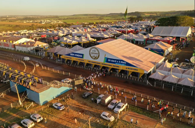 Vista aérea da Agrishow em Ribeirão Preto com pavilhões, estandes e público circulando na feira agrícola