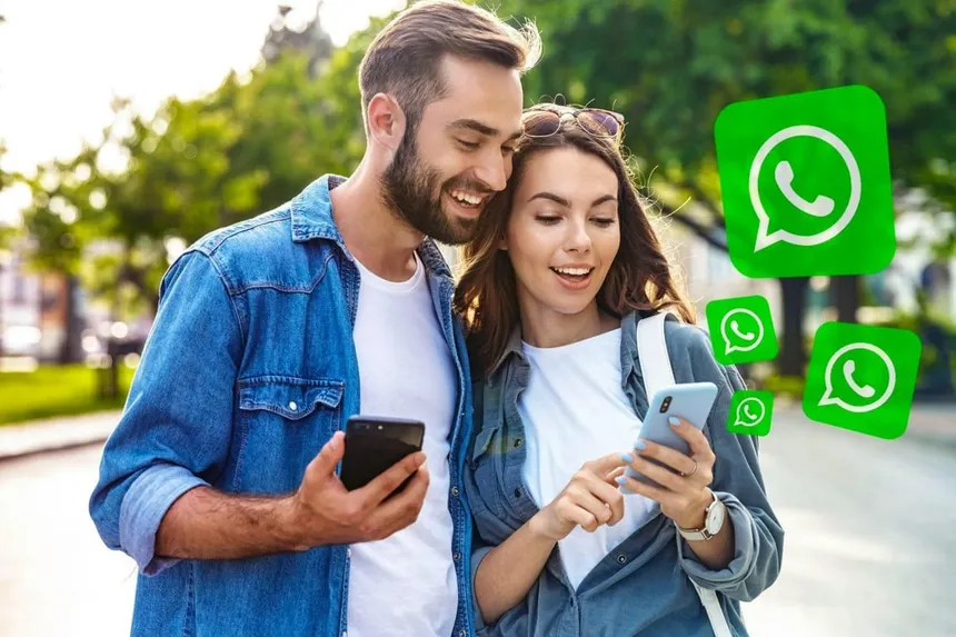 Casal usa celular com símbolos do WhatsApp em destaque para ilustrar comunicação pelo aplicativo