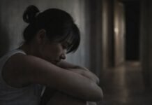 Em 2025, maioria das agressões contra mulheres aconteceu dentro de casa Mulher em ambiente doméstico escuro, em posição de vulnerabilidade, ilustrando violência doméstica e agressões contra mulheres