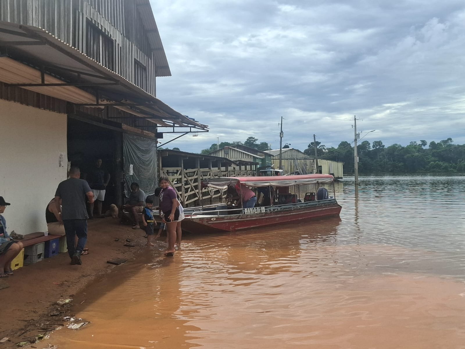 Comunidade ribeirinha em Porto Velho afetada pela cheia do Rio Madeira, com barco próximo às casas