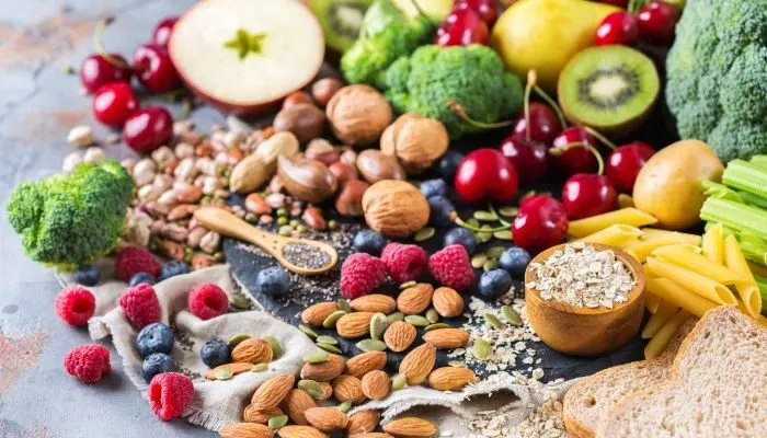 Alimentos ricos em fibra e proteína com frutas, cereais, castanhas e vegetais
