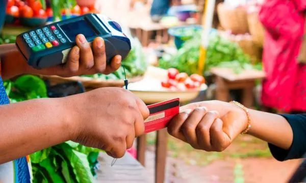 Pagamento com cartão em máquina durante compra de alimentos em feira livre