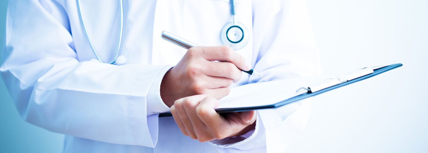 Médico com estetoscópio preenchendo prontuário durante atendimento para exames preventivos