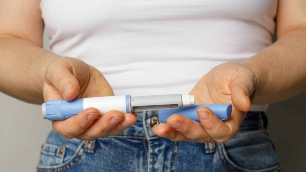 Pessoa segura caneta emagrecedora em imagem ilustrativa sobre medicamentos para perda de peso