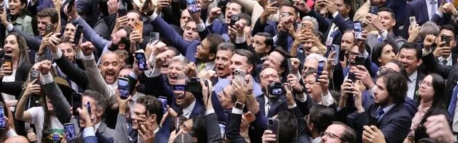 Pessoas comemorando com celulares levantados.