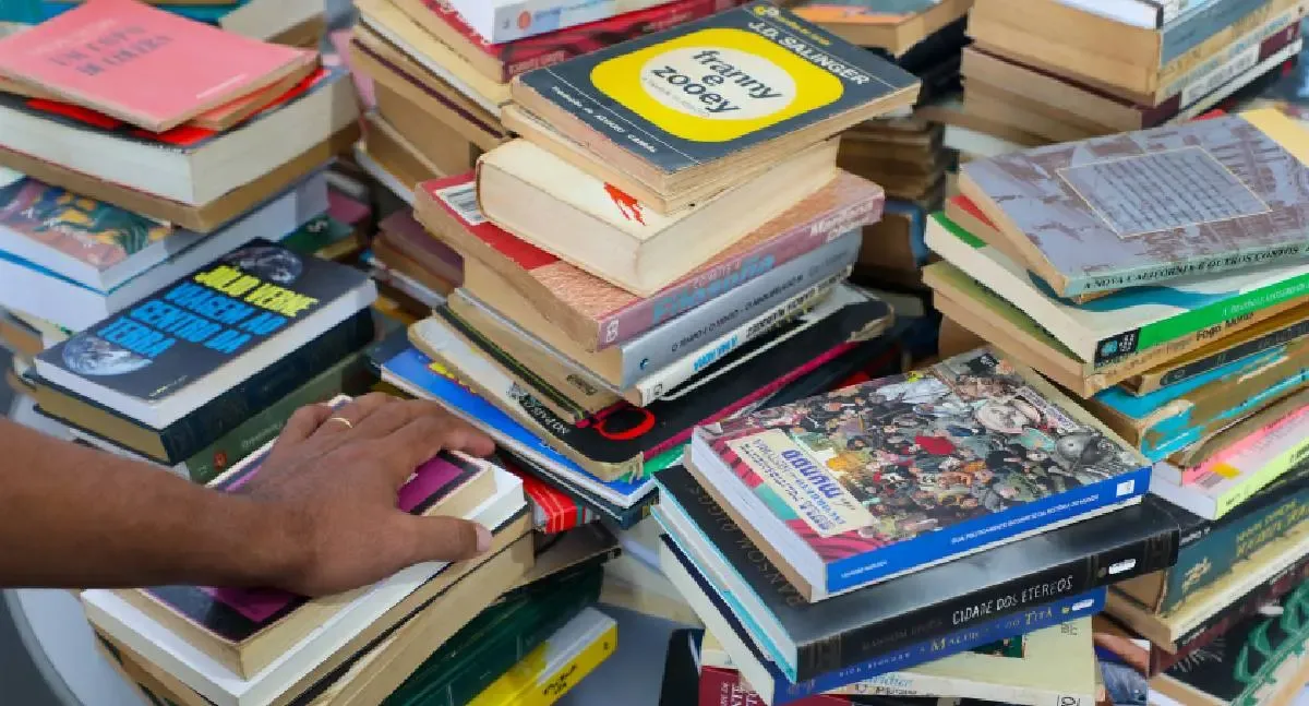 Pilhas de livros empilhados desordenadamente.