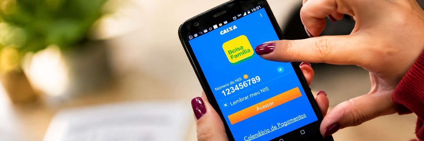 Pessoa acessa o aplicativo do Bolsa Família pelo celular para consultar informações do benefício