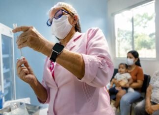 Central de vacinas em Porto Velho já aplicou 614 doses especiais Profissional de saúde prepara dose na central de vacinas em Porto Velho com pacientes aguardando atendimento especial