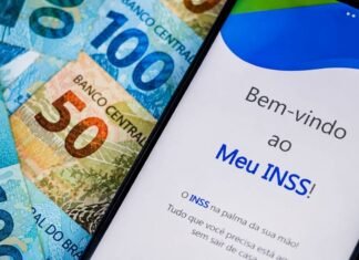 INSS exige biometria facial e muda regras do consignado para aposentados Celular com aplicativo Meu INSS sobre cédulas de dinheiro, representando novas regras do empréstimo consignado do INSS.