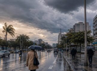 Frente fria no Brasil provoca chuva e queda de temperatura Frente fria no Brasil provoca chuva em avenida urbana com pessoas usando guarda-chuvas e céu nublado