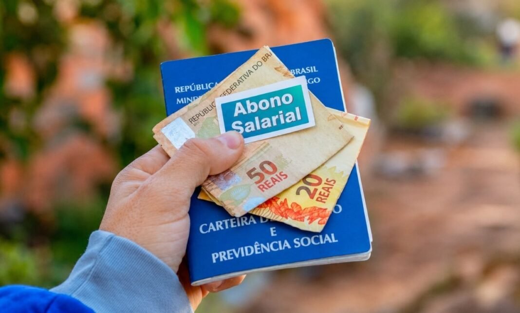 Carteira de trabalho com notas de real representando pagamento do abono salarial 2026