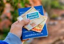 Abono salarial 2026 começa a ser pago para nascidos em maio e junho Carteira de trabalho com notas de real representando pagamento do abono salarial 2026