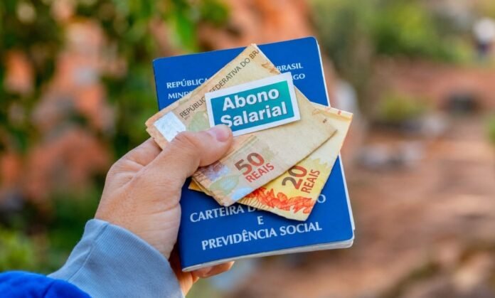 abono salarial 2026 Carteira de trabalho com notas de real representando pagamento do abono salarial 2026