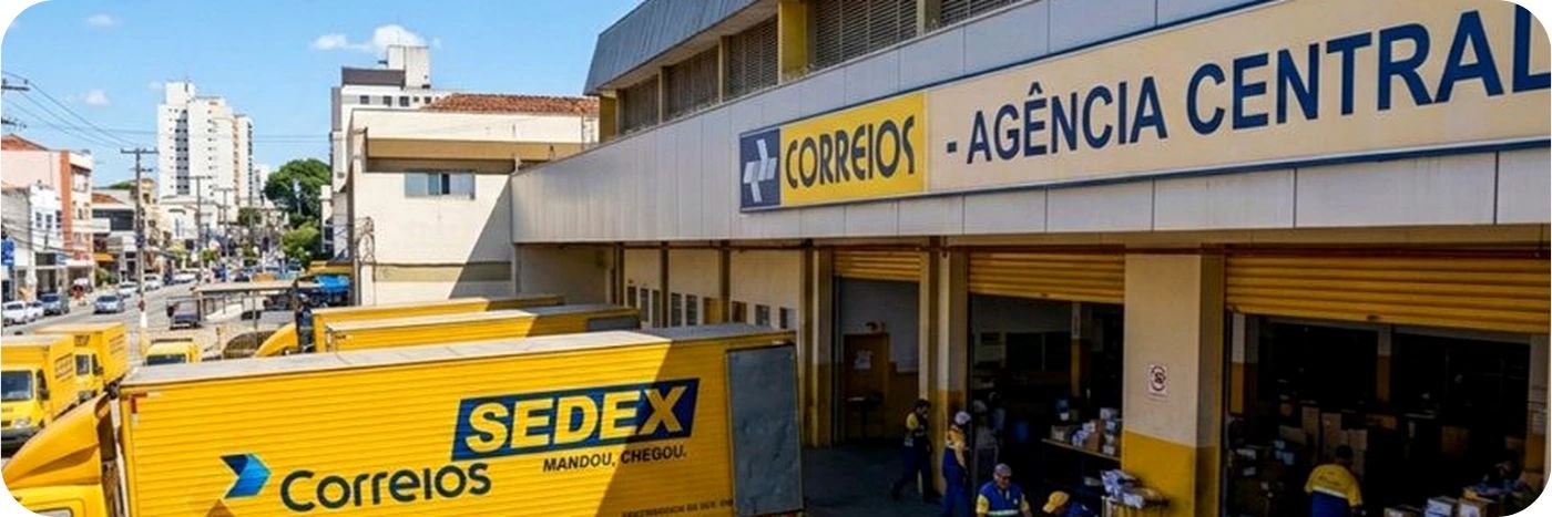 Agência central dos Correios com veículos amarelos, caminhão Sedex e funcionários organizando encomendas.