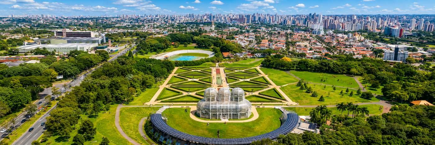 Vista aérea de Curitiba com jardim botânico, áreas verdes e skyline urbano em destaque no ranking de qualidade de vida