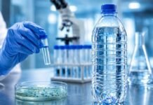 Entenda o risco da Pseudomonas aeruginosa achada em lote de água Garrafa de água mineral em bancada de laboratório durante análise sanitária relacionada à Pseudomonas aeruginosa