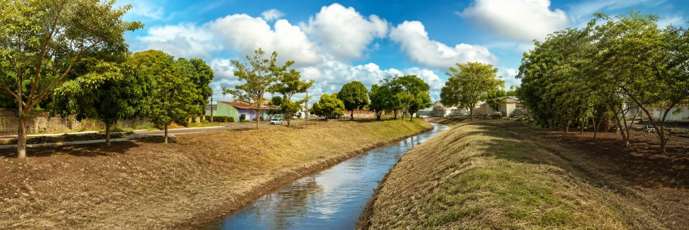 Imagem-faixa mostra igarapé urbano limpo em Porto Velho, com canal desobstruído e margens organizadas.
