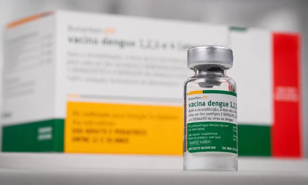 Vacina da dengue do Butantan suspensa pelo Ministério da Saúde Frasco da vacina da dengue do Butantan em destaque, com embalagem ao fundo, após suspensão temporária pelo Ministério da Saúde.