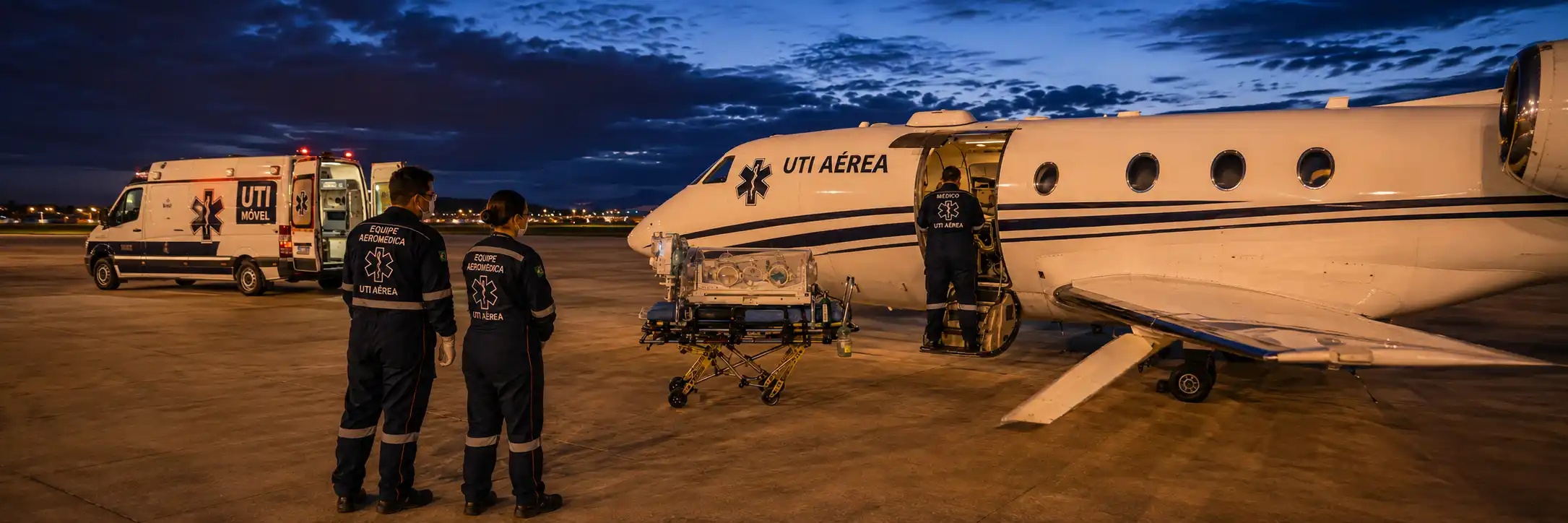 UTI aérea com equipe, aeronave e ambulância durante preparação de transporte aeromédico.