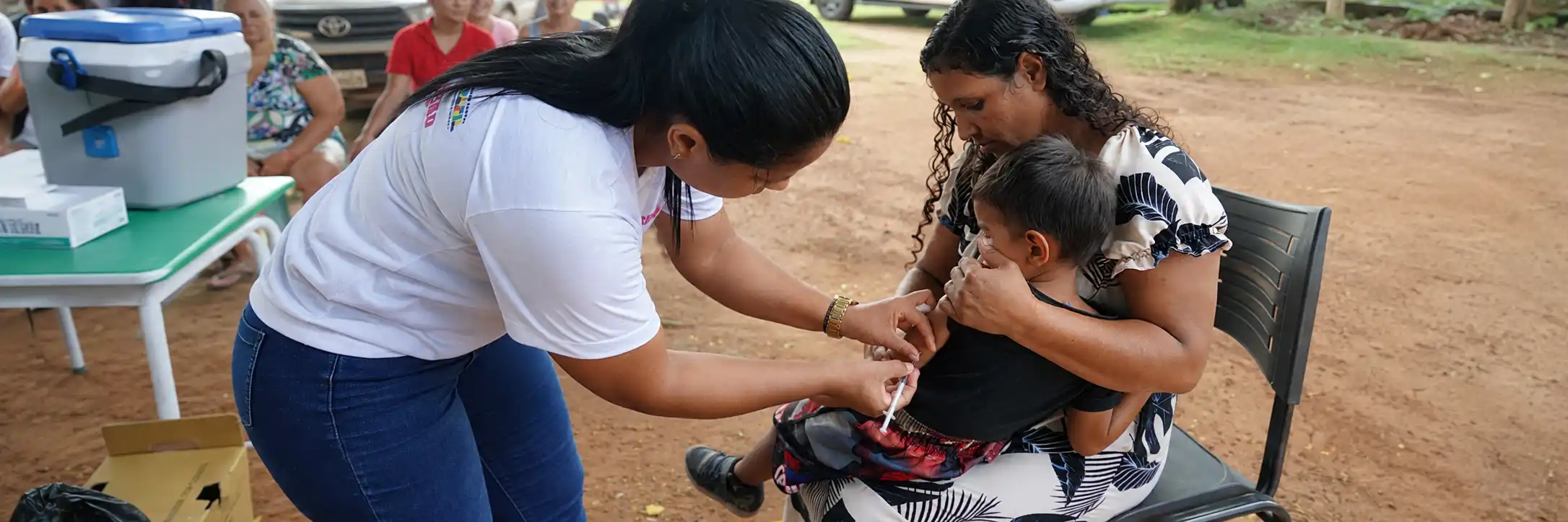 Atendimento da multivacinação em Rondônia mostra profissional de saúde vacinando criança acompanhada pela família.
