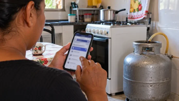 Gás do Povo em Rondônia Gás do Povo em Rondônia com responsável familiar consultando benefício pelo celular ao lado de botijão de gás