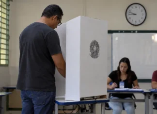 Eleições 2026: Rondônia terá votação das 7h às 16h Eleitor vota em seção eleitoral de Rondônia com relógio ao fundo indicando o horário de votação