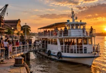 Porto Velho anuncia 1.500 ingressos gratuitos para passeios no Rio Madeira Imagem ilustrativa de embarque em barco de passeio no Rio Madeira ao pôr do sol, perto da Estrada de Ferro Madeira-Mamoré