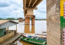 Defesa Civil alerta para bancos de areia e encalhamentos no Rio Madeira Composição visual baseada em fotografia fornecida pelo editor mostra o nível do Rio Madeira, régua fluviométrica, ponte e embarcações em Porto Velho.