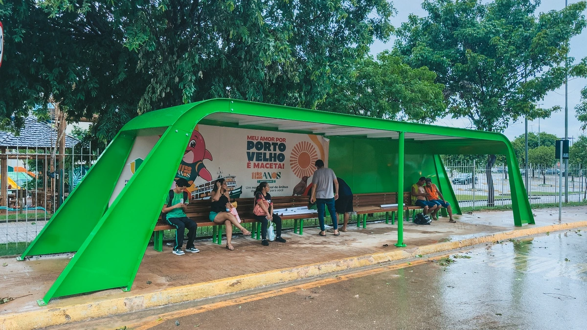 Porto Velho instala segundo Terminal Arco em frente ao shopping com USB solar Terminal Arco em Porto Velho com cobertura verde e passageiros aguardando ônibus em frente ao shopping, em fotografia real do novo abrigo.